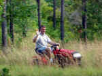 Alan waves "hi" while mowing a nature trail on his property